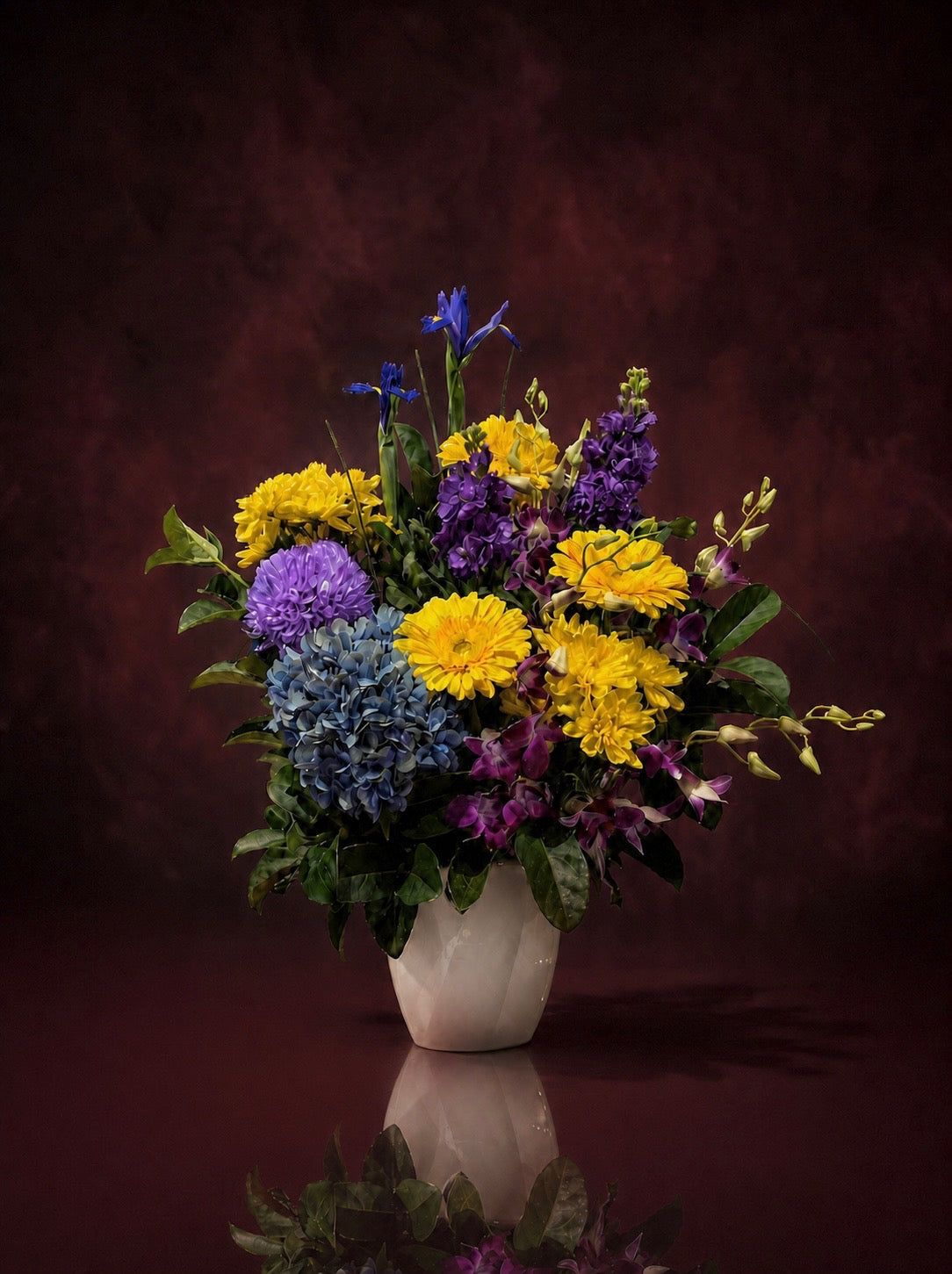 The Florist's Edit boxed arrangement in yellow, purple and blue: iris, hydrangea, chrysanthemums and dendrobium orchids in a white ceramic vase