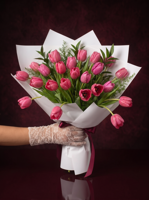 Tulips, the Signature: a full armful of pink tulips hand-wrapped in white paper and tied with a burgundy ribbon, held in a lace-gloved hand, made in Surfers Paradise