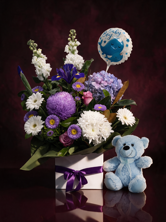 The Nursery in blue: white stocks, blue iris, hydrangea and purple asters in a white box with a purple ribbon, beside a blue teddy bear and a Baby Boy balloon, made in Surfers Paradise