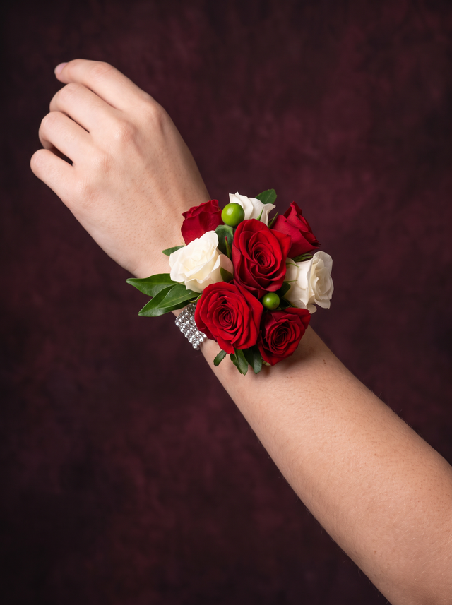 Wrist corsage of red and white roses with green hypericum berries on a diamanté band, worn on the wrist